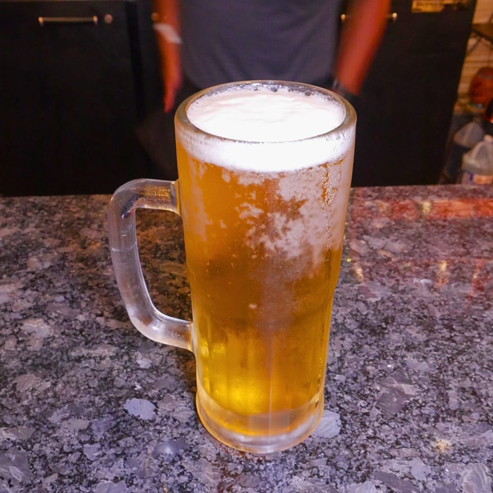 Frosted glass mug of golden beer with a thick foamy head on a granite restaurant countertop.